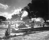 FILE - In this photo provided by the U.S. Navy, U.S. sailors stand among wrecked airplanes at Ford Island Naval Air Station as they watch the explosion of the USS Shaw in the background, during the Japanese attack on Pearl Harbor, Hawaii, Dec. 7, 1941. In December 2022, the U.S. Navy and the National Park Service will host a remembrance ceremony at Pearl Harbor on the 81st anniversary of the 1941 Japanese bombing. (U.S. Navy via AP, File)