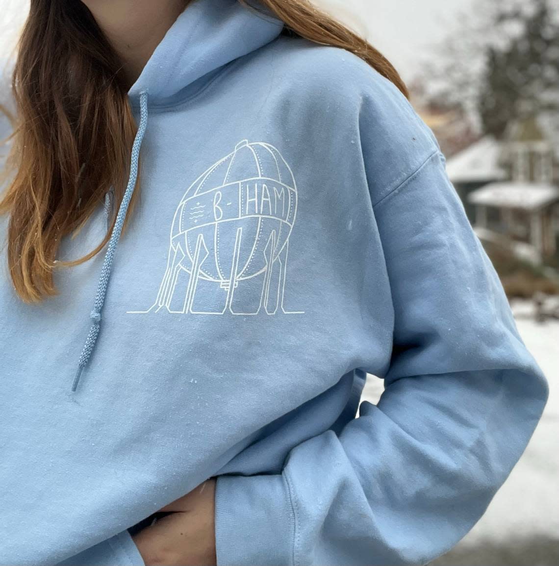 Local artist Tabitha Smed wears a hooded sweatshirt with her acid ball design printed on it that is available for purchase on her Etsy shop.