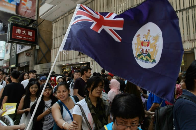 The British colonial-era Hong Kong flag is seen as weekend pedestrians walk past a holding area for demonstrating activists ahead of a rally against the banning of pro-independence candidates in the upcoming legislative council elections