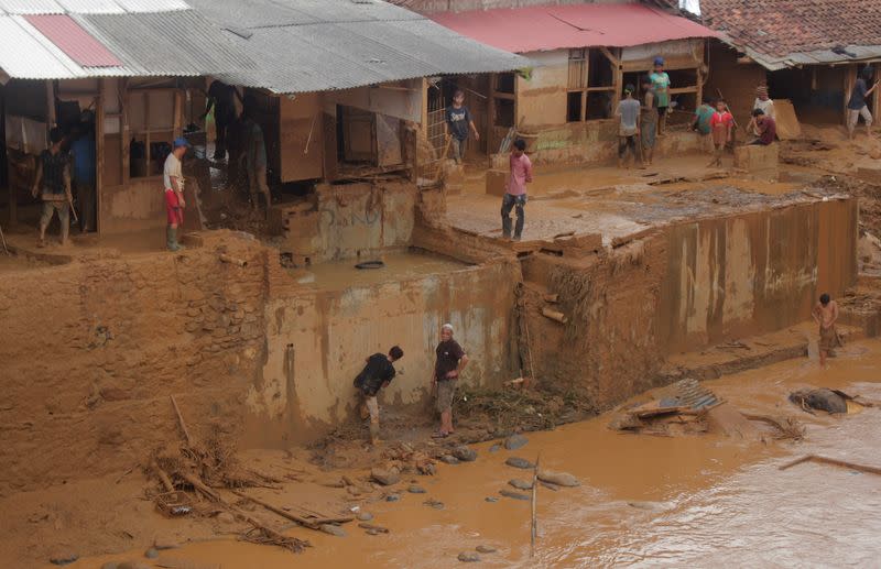 People clean up the clay after floods hit Lebak Gendong, Banten