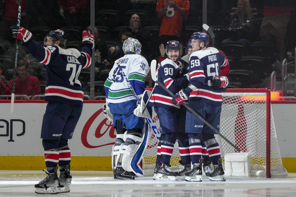 Washington Capitals defenseman John Carlson (74), left wing Marcus Johansson (90), center Lars Eller, second from right, and center Aliaksei Protas (59) celebrate a goal against Vancouver Canucks goaltender Thatcher Demko (35) during the second period of an NHL hockey game, Monday, Oct. 17, 2022, in Washington. (AP Photo/Jess Rapfogel)