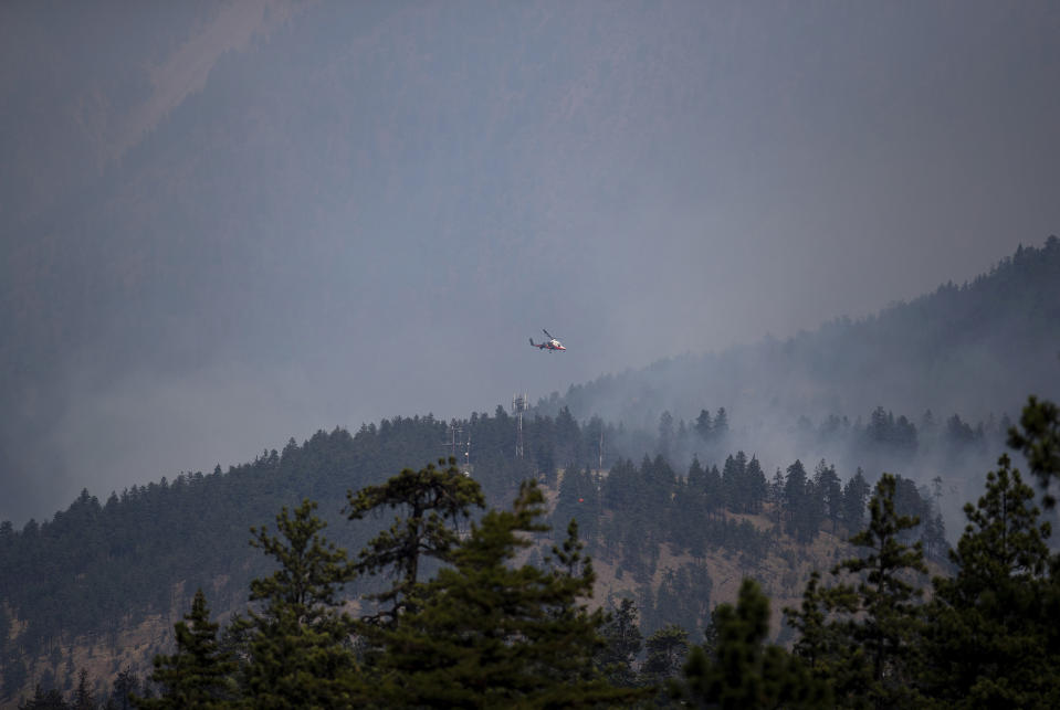 A helicopter pilot prepares to drop water on a wildfire burning in Lytton, British Columbia, Friday, July 2, 2021. Officials on Friday hunted for any missing residents of the British Columbia town destroyed by wildfire as Canadian Prime Minister Justin Trudeau offered federal assistance. (Darryl Dyck/The Canadian Press via AP)