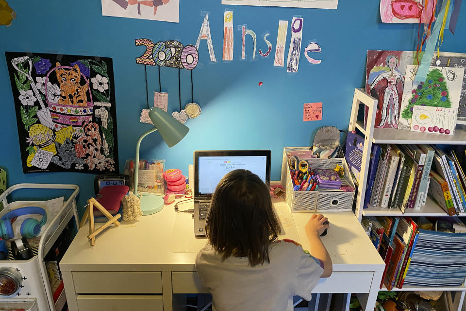 This April 9, 2020, photo released by Kara Illig shows her daughter, Ainslie Illig, 8, on her computer in Ebensburg, Pa. The frustration of parents is mounting as more families across the U.S. enter their second or even third week of total distance learning, and some say it will be their last. (Kara Illig via AP)