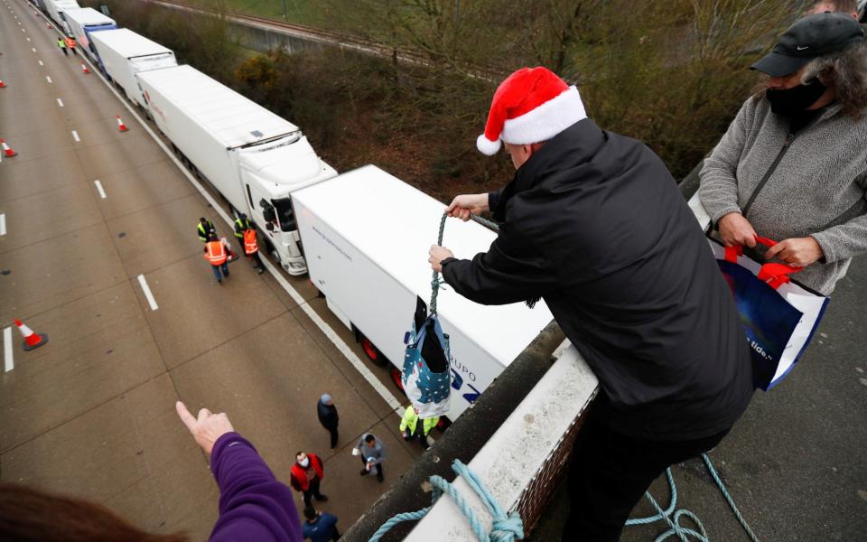 People use a rope to hand supplies to drivers as lorries queue at the M20 motorway near Ashford - Peter Nicholls/Reuters