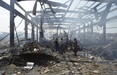 Men walk at the site of a Saudi-led air strike targeted at Public Electricity Corporation branch in Yemen's western city of Hodeidah October 11, 2015. REUTERS/Stringer