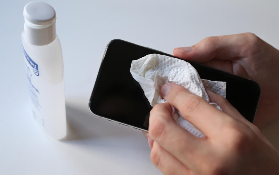 16 March 2020, Bavaria, Kempten: A young man disinfects his smartphone with a paper towel and disinfectant. Photo: Karl-Josef Hildenbrand/dpa (Photo by Karl-Josef Hildenbrand/picture alliance via Getty Images)