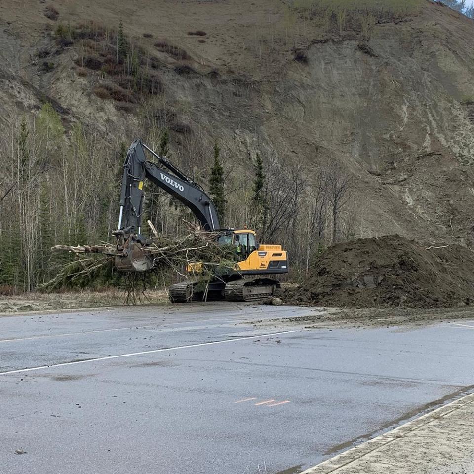 An excavator helps clean up the debris from the April 30 landslide on Robert Service Way in Whitehorse on May 26, 2022.