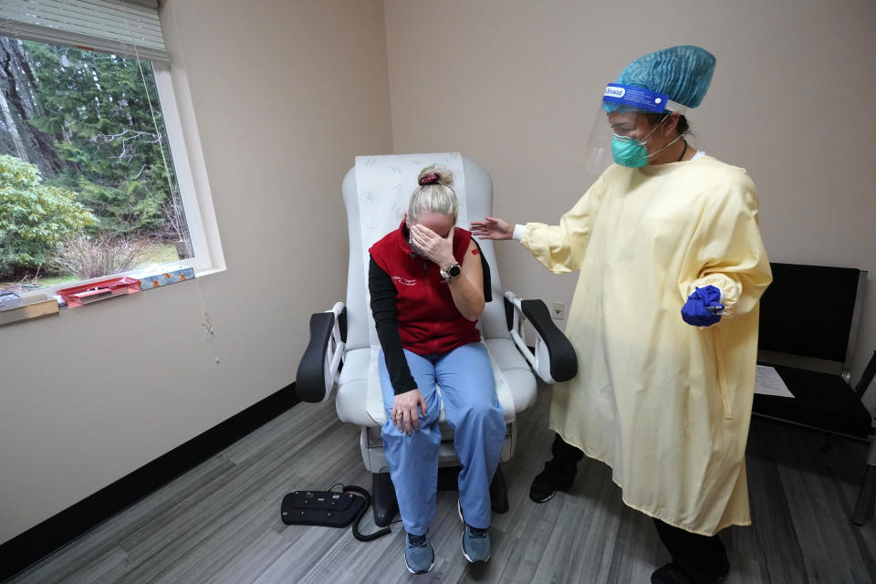 Medical worker Melissa Fitzgerald begins to weep in an emotional response after receiving a COVID-19 vaccination from registered nurse Alyssa Lane Thursday, Dec. 17, 2020, on the Lummi Reservation, near Bellingham, Wash. Fitzgerald, a radiologic technician, has been treating coronavirus patients since the outbreak began on the reservation on her birthday in March and said it's been a long journey. The Native American tribe began rationing its first 300 doses of vaccine as it fights surging cases with a shelter-in-place order. (AP Photo/Elaine Thompson)