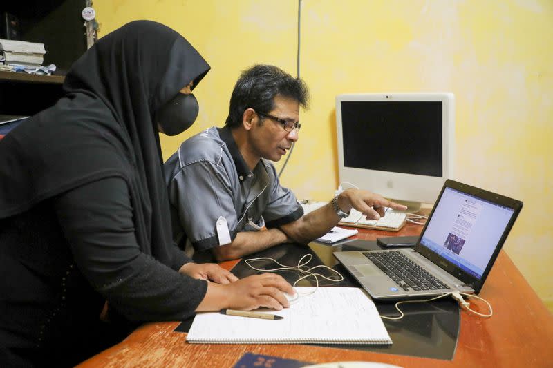 Rohingya refugee and activist Zafar Ahmad Abdul Ghani and his wife look at a computer screen displaying the threats and hate speech they received, at their home in Kuala Lumpur