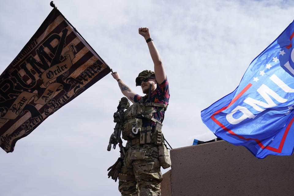 An armed supporter of President Donald Trump raises his fist while standing outside of the Clark County Elections Department in North Las Vegas, Nev., Saturday, Nov. 7, 2020. Democrat Joe Biden defeated President Donald Trump to become the 46th president of the United States on Saturday, positioning himself to lead a nation gripped by the historic pandemic and a confluence of economic and social turmoil. (AP Photo/John Locher)