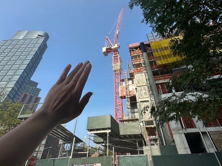 A woman's arm as she waves at a crane in the distance.