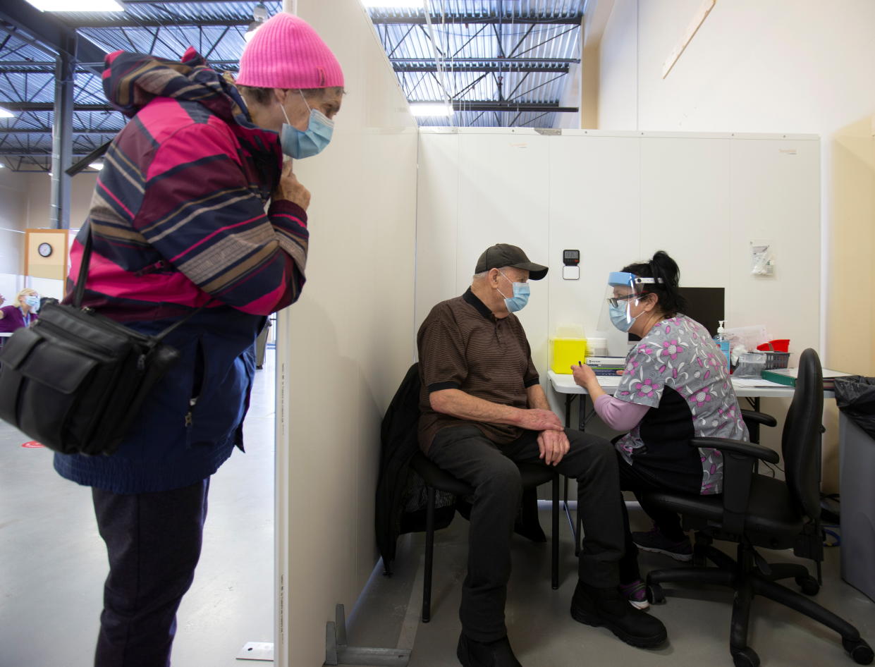 Helene Jolicoeur watches as her 88 year old husband Robert Proteau gets vaccinated against the coronavirus disease (COVID-19) in a clinic in Laval, Quebec, Canada February 25, 2021. REUTERS/Christinne Muschi