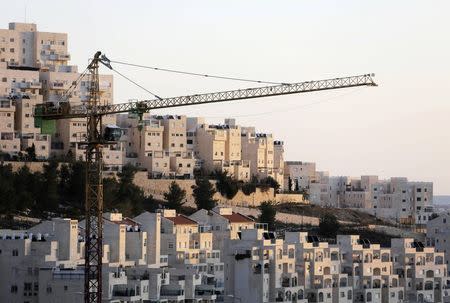 A crane is seen next to homes in a Jewish settlement known to Israelis as Har Homa and to Palestinians as Jabal Abu Ghneim, in an area of the West Bank that Israel captured in a 1967 war and annexed to the city of Jerusalem, in this January 3, 2014 file photo. REUTERS/Ammar Awad/Files