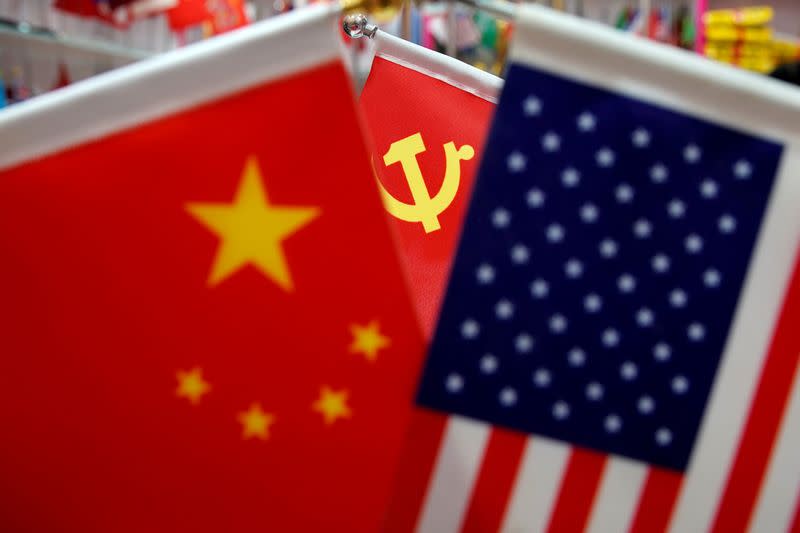 FILE PHOTO: The flags of China, the United States and Chinese Communist Party are displayed in a flag stall at the Yiwu Wholesale Market in Yiwu