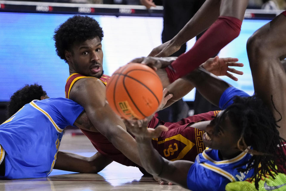 Southern California guard Bronny James, center, scrambles for the ball against UCLA forward Devin Williams, left, and guard Will McClendon, right, during the first half of an NCAA college basketball game, Saturday, Jan. 27, 2024, in Los Angeles. (AP Photo/Ryan Sun)