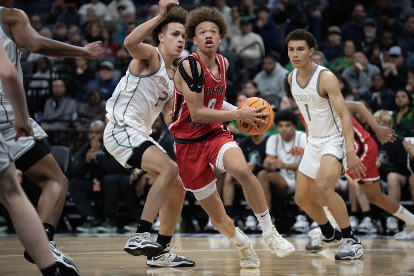 Harvard-Westlake's Trent Perry (0) drives past St. Joseph's Luis Marin (2) for a basket in the first quarter.