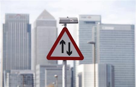 A traffic sign is pictured in front of the skyline of the the Canary Wharf financial district in London in this October 21, 2010 file photo. REUTERS/Luke Macgregor/Files