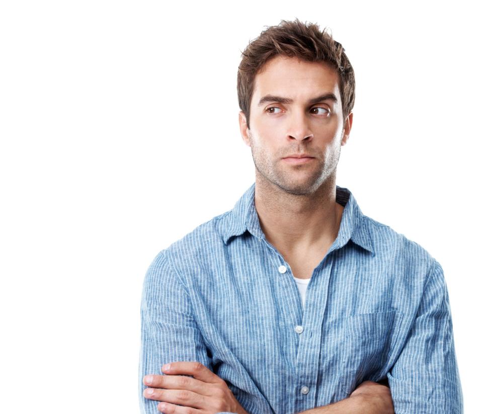 Man in a casual shirt with arms crossed, looking to the side with a thoughtful expression