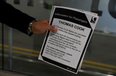 A man holds information on Thomas Cook flights at Manchester Airport
