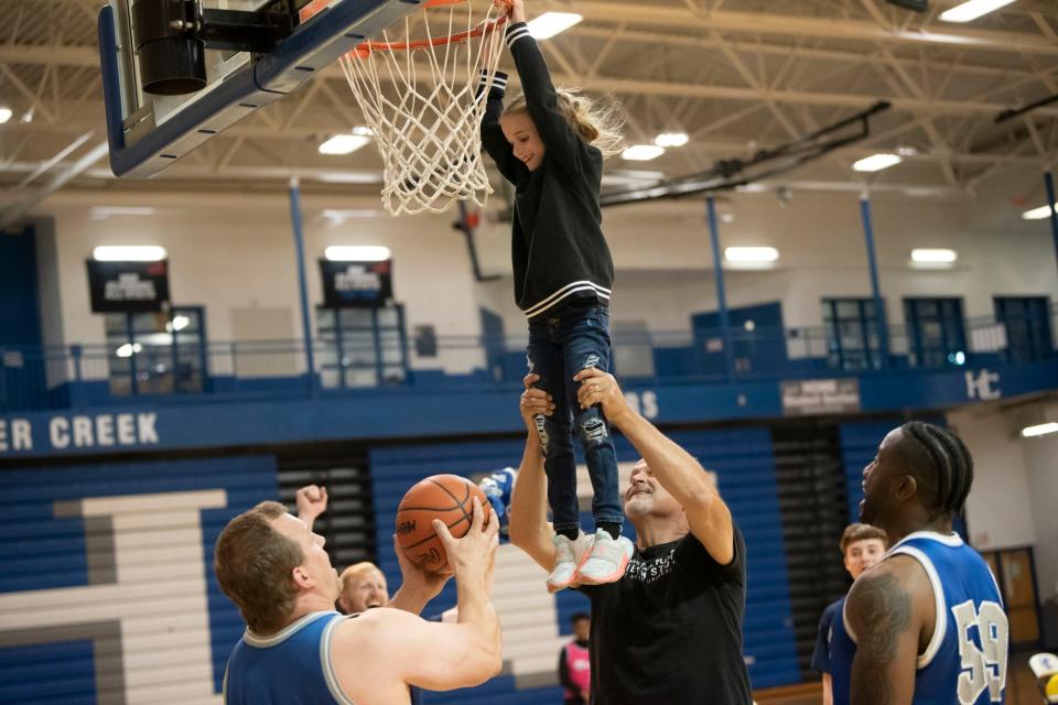 Former Detroit Lions players lift children up to the basket at Harper Creek High School on Tuesday, May 17, 2022.