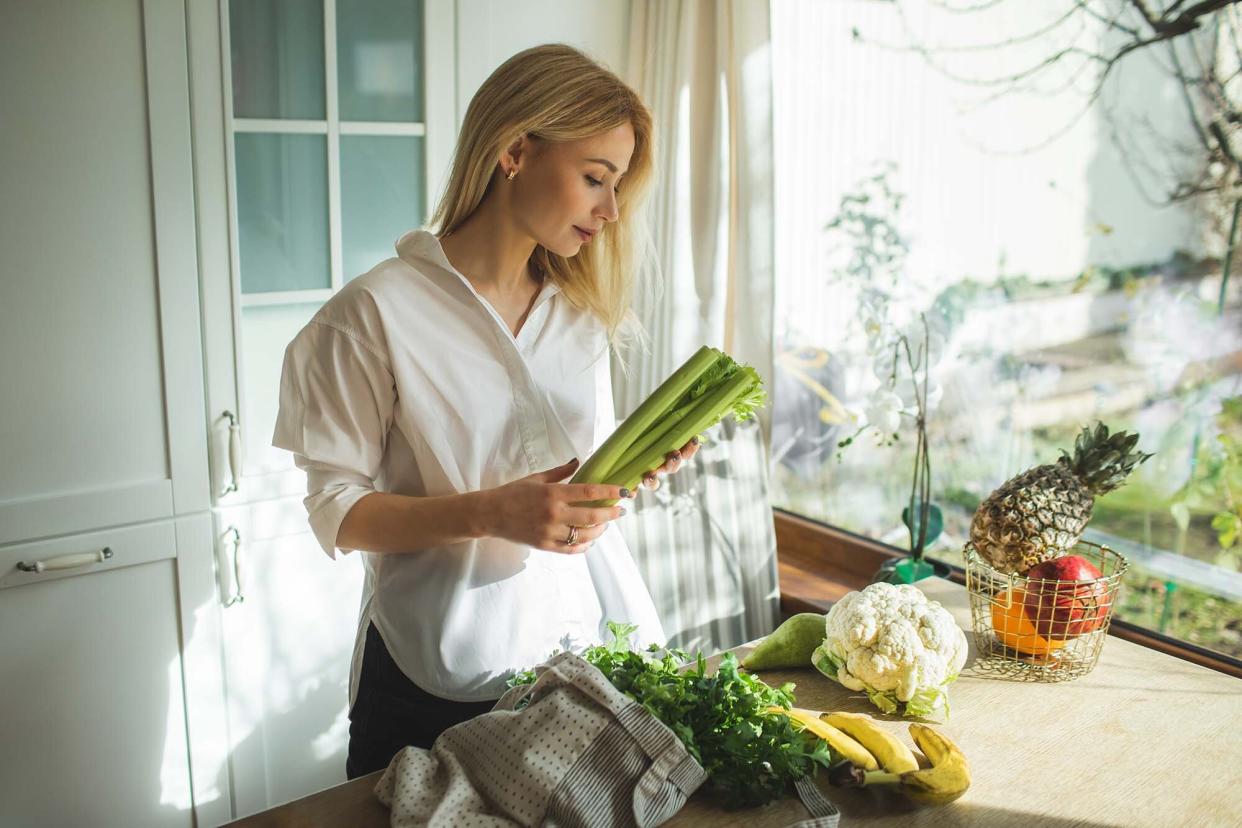 woman unpacks a full fabric bag with fruits and vegetables on the kitchen