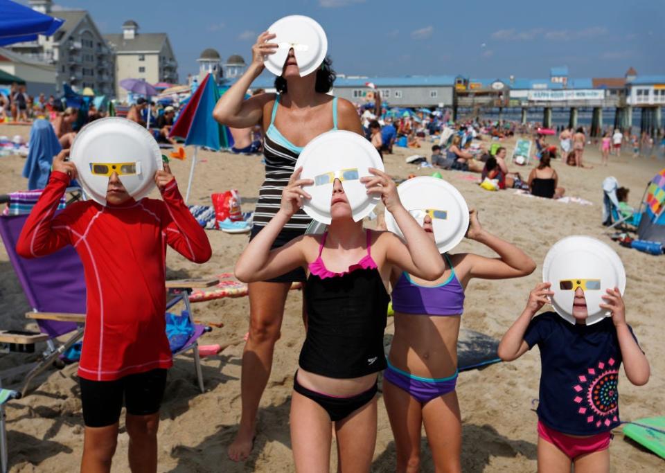 File: Members of two vacationing families observe a partial solar eclipse through some hand-improved solar glasses at Old Orchard Beach, Maine.