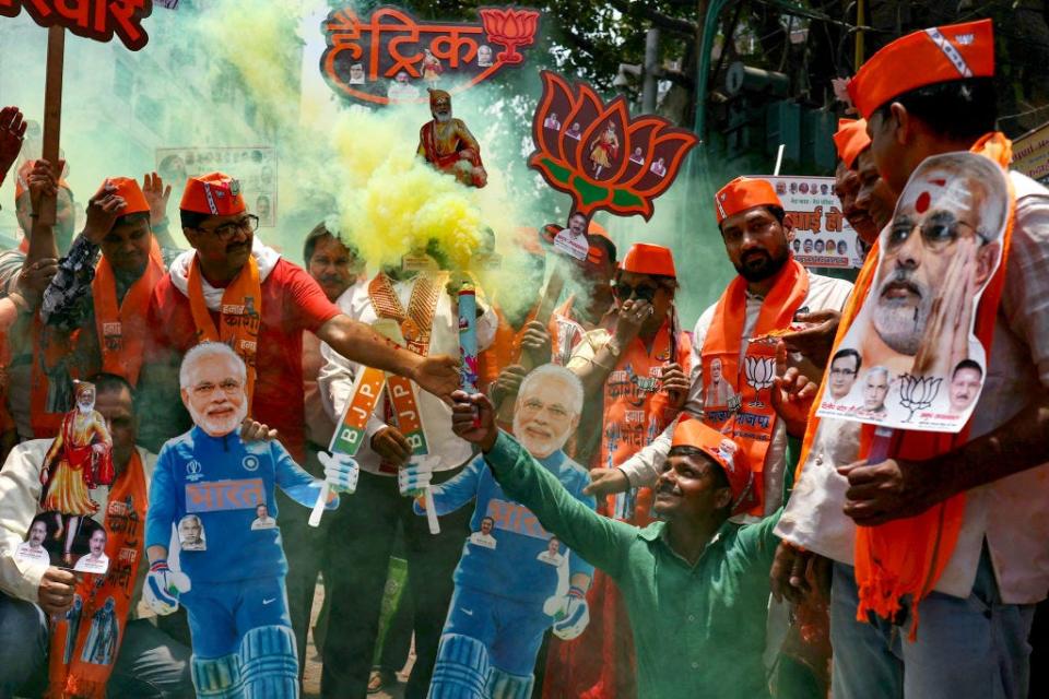 People carrying cutouts of Narendra Modi and setting off flares.