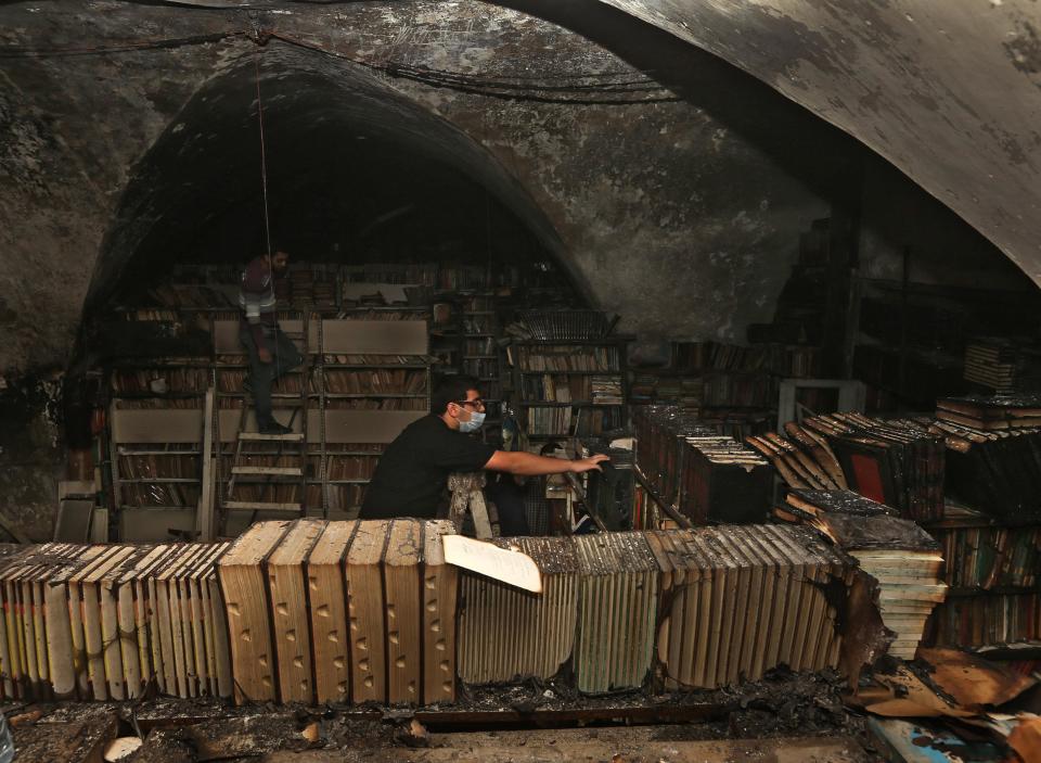 In this picture taken on Sunday, Jan. 5, 2014, Lebanese activists stand on wooden ladders remove and clean burned books, at the Saeh (Tourist) Library which was set on fire by masked men, in the northern city of Tripoli, Lebanon. Books that were burnt in an arson attack targeting a crammed, chaotic and popular library in the northern Lebanese city of Tripoli have become the latest victim of the country's rising sectarian tensions.(AP Photo/Hussein Malla)