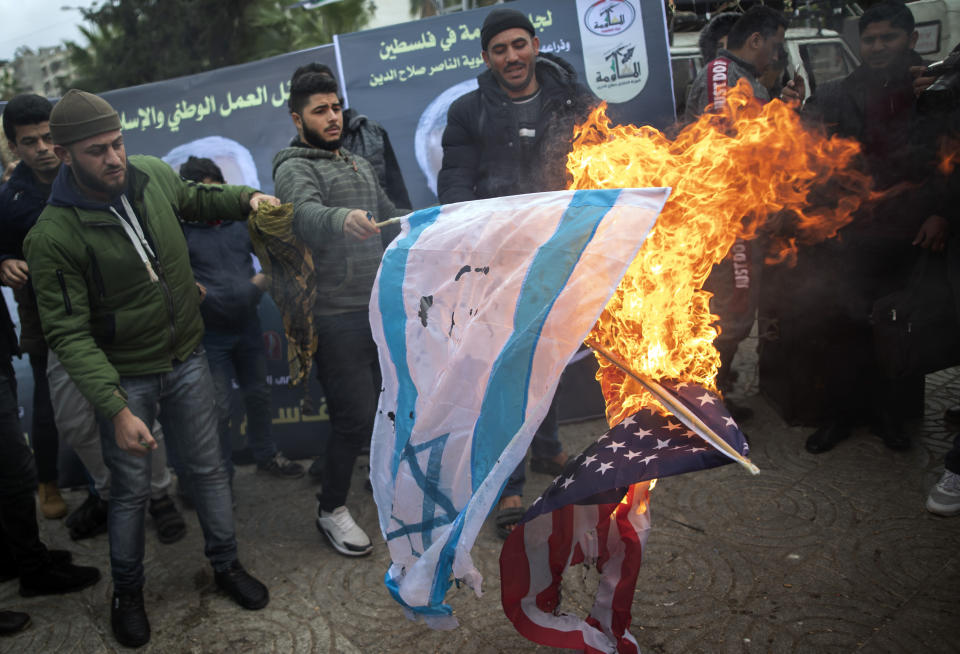 Palestinians burn US and Israeli flags as they attend a mourning tent held by Palestinian factions for Qassem Soleimani, the Iran's head of the Quds Force, who was killed in a US drone strike early Friday, in Gaza City, Saturday, Jan 4, 2020. (AP Photo/Khalil Hamra)