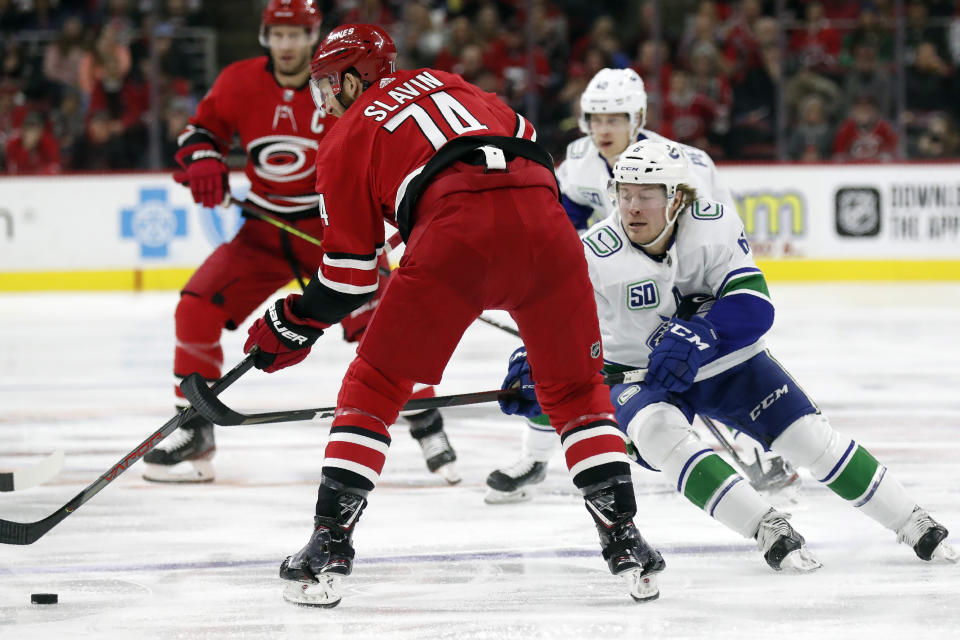 Carolina Hurricanes defenseman Jaccob Slavin (74) passes the puck while Vancouver Canucks right wing Brock Boeser (6) defends during the first period of an NHL hockey game in Raleigh, N.C., Sunday, Feb. 2, 2020. (AP Photo/Gerry Broome)