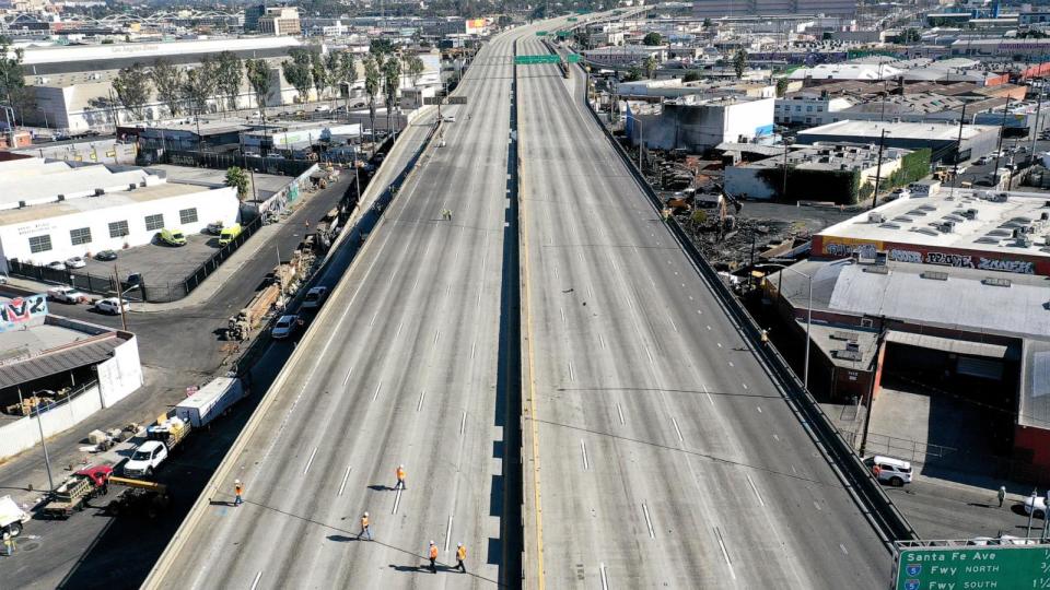 PHOTO: An aerial view of workers walking on the closed I-10 freeway following a large pallet fire, which occurred Saturday at a storage yard, on Nov. 13, 2023 in Los Angeles. (Mario Tama/Getty Images)