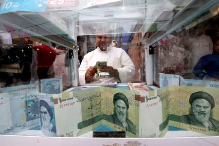 FILE PHOTO: A man counts Iranian rials at a currency exchange shop, before the start of the U.S. sanctions on Tehran, in Basra