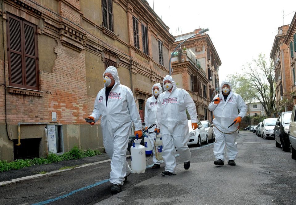 Workers wearing protective outfits sanitize a neighborhood to contain the spread of Covid-19 virus, in Rome, Saturday, March 28, 2020. The new coronavirus causes mild or moderate symptoms for most people, but for some, especially older adults and people with existing health problems, it can cause more severe illness or death. (Mauro Scrobogna/LaPresse via AP)