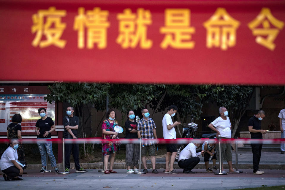 Residents line up for Covid-19 tests near a banner with the words "Epidemic is the Order" in Wuhan in central China's Hubei province Tuesday, Aug. 3, 2021. China's worst coronavirus outbreak since the start of the pandemic a year and a half ago escalated Wednesday with dozens more cases around the country, the sealing-off of one city and the punishment of its local leaders. (Chinatopix Via AP)