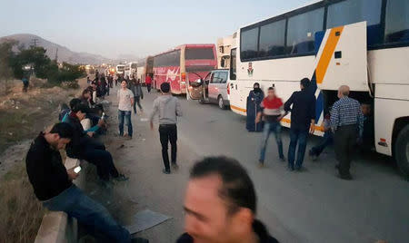 People gather near buses as they wait to be evacuated from the town of Douma, eastern Ghouta, in Damascus, Syria April 1, 2018. REUTERS/Bassam Khabieh