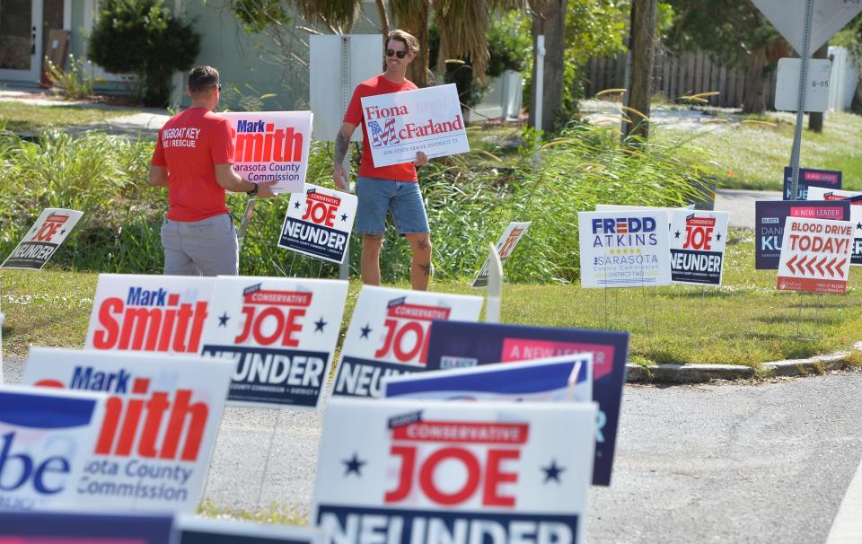 Members of the Longboat Key Fire Dept. wave campaign signs for Republican candidates along Riverwood Ave. near the polling place at Trinity United Methodist Church in Sarasota, Florida on Tuesday, Nov. 8, 2022.  
