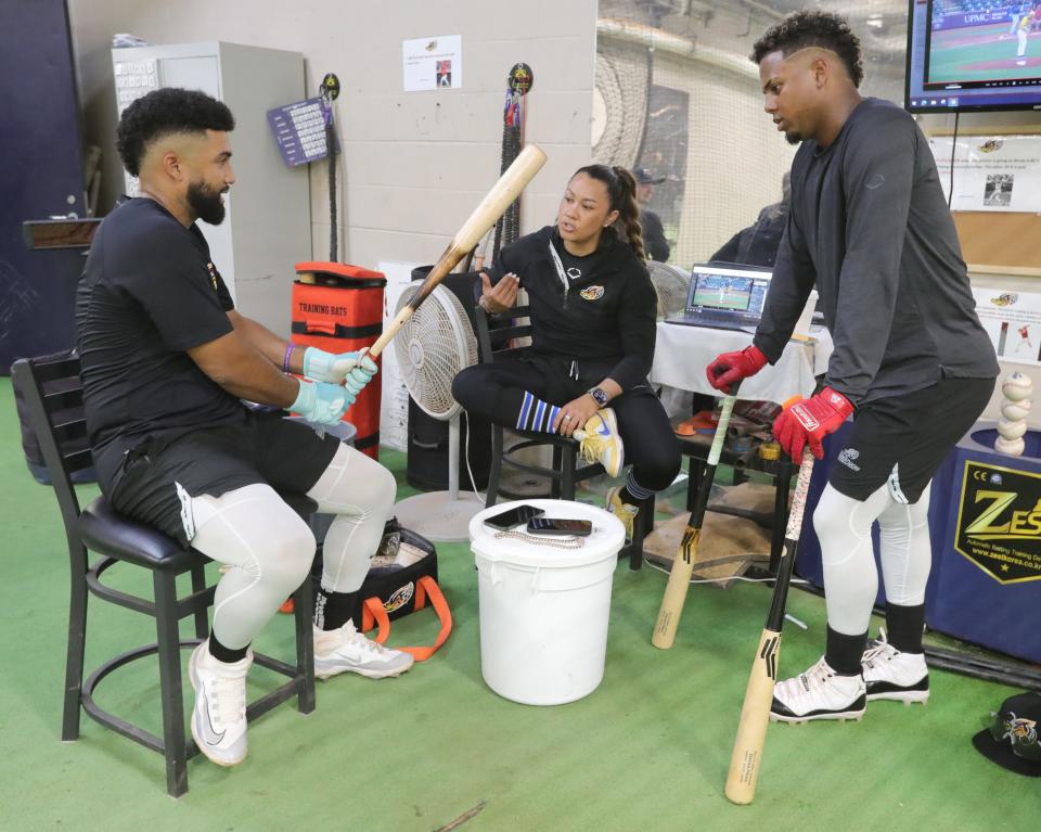 RubberDucks assistant hitting coach Amanda Kamekona talks shop with Akron players Aaron Bracho, left, and Dayan Frias.