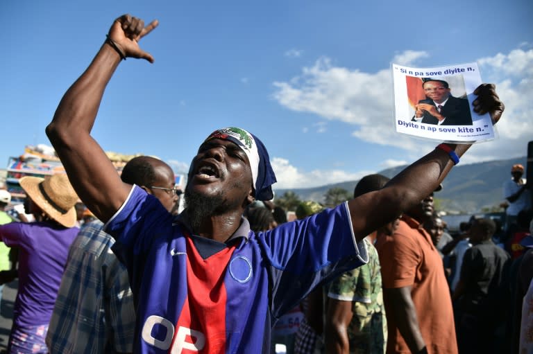 A demonstrator holds a picture of former Haitian President Jean Bertrand Aristide during a march of opposition political parties, in Port-au-Prince, on February 12, 2016