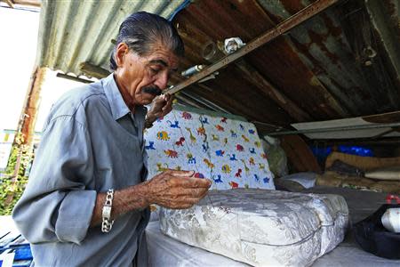 Mattress repairman and fruit vendor Angelo Lopez sews a cushion in the shed which he calls his factory in Lares, western Puerto Rico, April 7, 2014. REUTERS/Ana Martinez