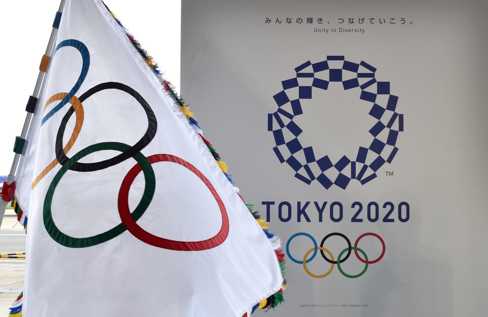 The Olympic flag (L) and the logo of the Tokyo 2020 are displayed during the official flag arrival ceremony at the Tokyo's Haneda airport on August 24, 2016. - The Olympic flag arrived in Tokyo on August 24, as Japan's capital gears up to host the 2020 Games, with officials promising smooth sailing after Rio's sometimes shaky 2016 instalment. (Photo by KAZUHIRO NOGI / AFP)        (Photo credit should read KAZUHIRO NOGI/AFP via Getty Images)