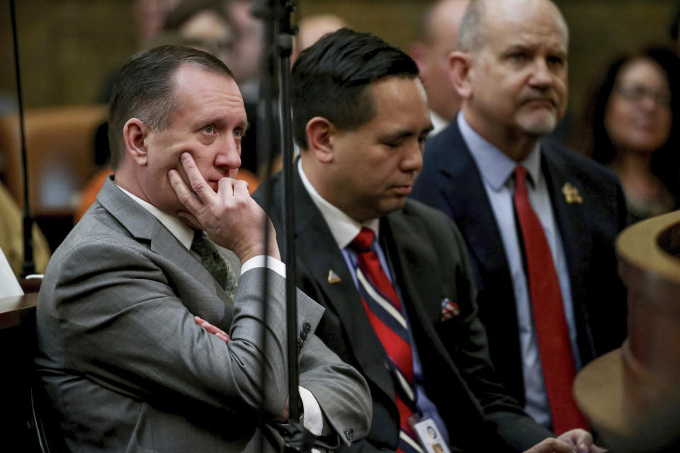 FILE - Utah Auditor John Dougall, left, listens as Gov. Gary Herbert delivers his State of the State address at the Utah State Capitol, on Jan. 30, 2019, in Salt Lake City. Transgender activists have flooded a Utah tip line created to alert state officials to possible violations of a new bathroom law with thousands of hoax reports in an effort to shield trans residents and their allies from any legitimate complaints that could threaten their safety. The onslaught has led the state official tasked by the law with managing the tip line, Dougall, to bemoan getting stuck with the cumbersome task of filtering through fake complaints while also facing backlash for enforcing a law he had no role in passing. (Spenser Heaps/The Deseret News via AP, Pool, File)