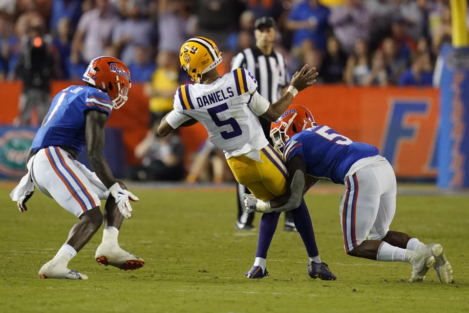 LSU quarterback Jayden Daniels (5) is stopped by Florida safety Kamari Wilson, right, and linebacker Brenton Cox Jr., left, as he tries to run from the pocket during the first half of an NCAA college football game, Saturday, Oct. 15, 2022, in Gainesville, Fla. (AP Photo/John Raoux)