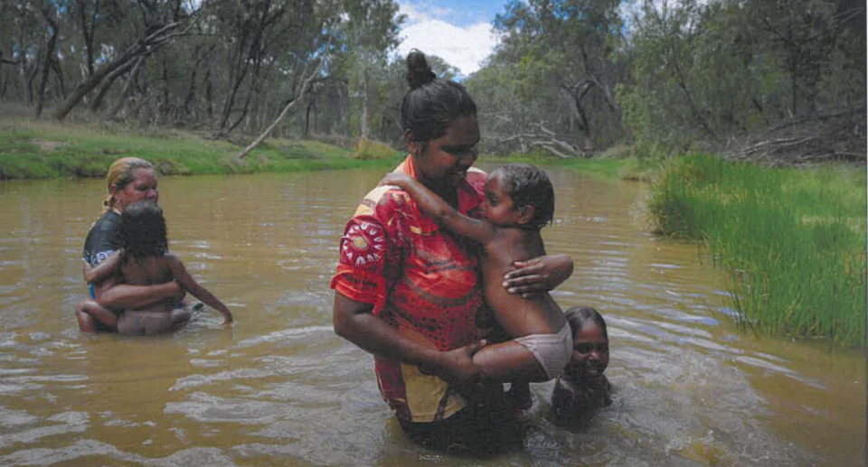 Indigenous women and children in the springs near Adani's mine.