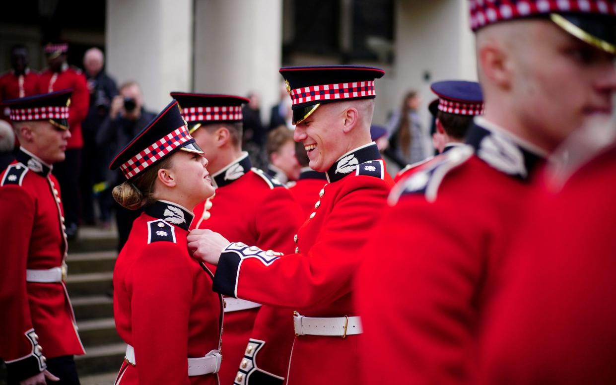 A Scots Guard member helps his colleague fix her uniform ahead of the Black Sunday Parade