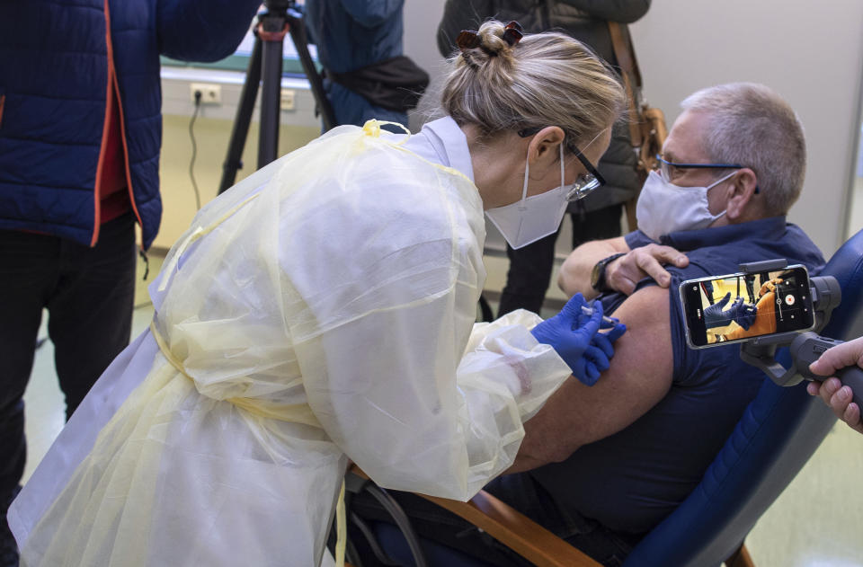 Nurse Ramona Radtke, left, injects paramedic Fred Knuth with the Pfizer/Biontech, vaccine at the vaccination center in Wismar, Germany, Tuesday, Jan. 12, 2021. In German federal state Mecklenburg-Western Pomerania, the first vaccination centers have started with vaccinations against the COVID-19 disease. (Jens Buettner/dpa via AP)