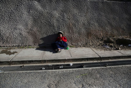 A woman lays on the sidewalk after attending a wedding party in the town of Nueva Fuerabamba in Apurimac, Peru, October 2, 2017. REUTERS/Mariana Bazo