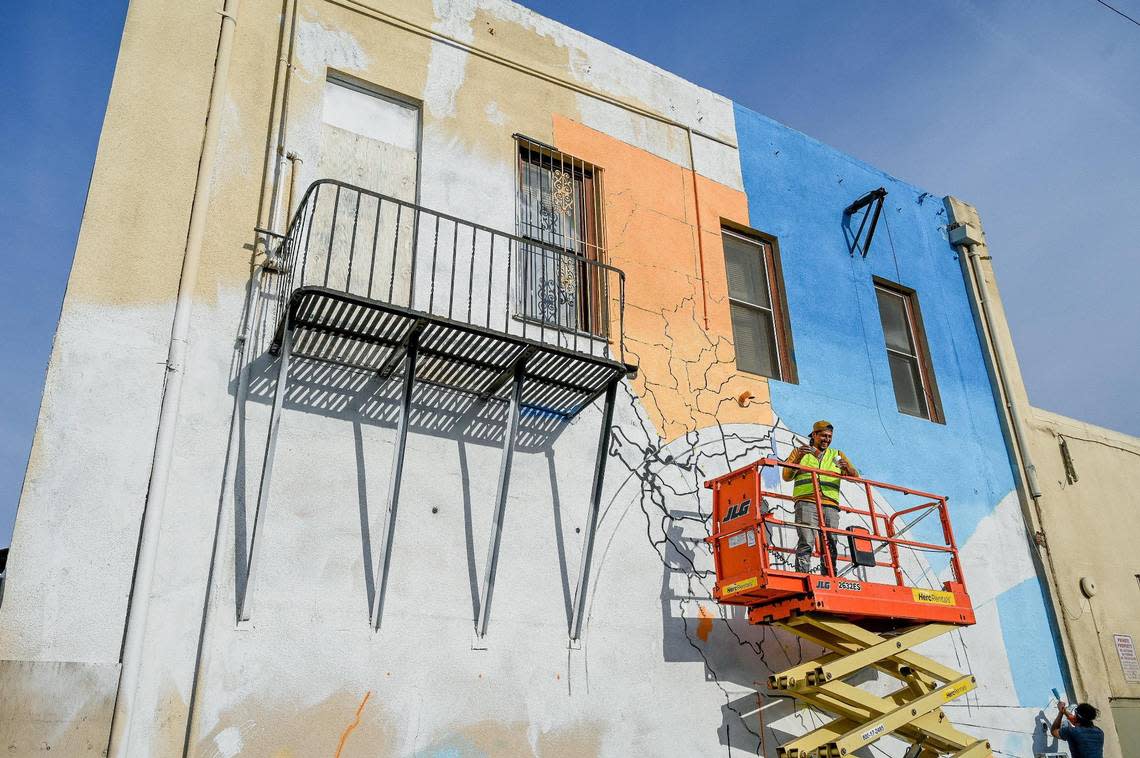 Fresno muralist Mauro Carrera, on lift, works with Rigo Garcia on a mural on a historical Chinatown building on China Alley in downtown Fresno on Thursday, Dec. 8, 2022. The project is in conjunction with the Fresno Arts Council and the California High-Speed Rail Authority.