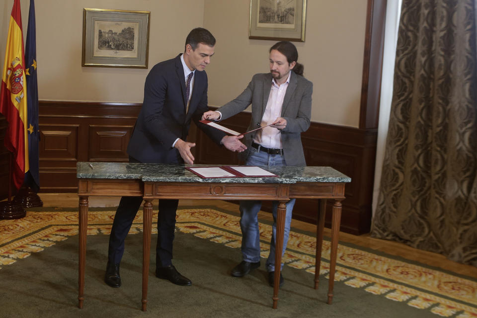 Spain's caretaker Prime Minister Pedro Sanchez, left, and Podemos party leader Pablo Iglesias exchange documents while signing an agreement at the parliament in Madrid, Spain, Tuesday, Nov. 12, 2019. The leaders of Spain's Socialist party and the left-wing United We Can (Podemos) party say they have reached a preliminary agreement toward forming a coalition government. But the deal announced Tuesday won't provide enough votes in parliament for the Socialists, who won a general election, to take office without the support of other parties. (AP Photo/Paul White)