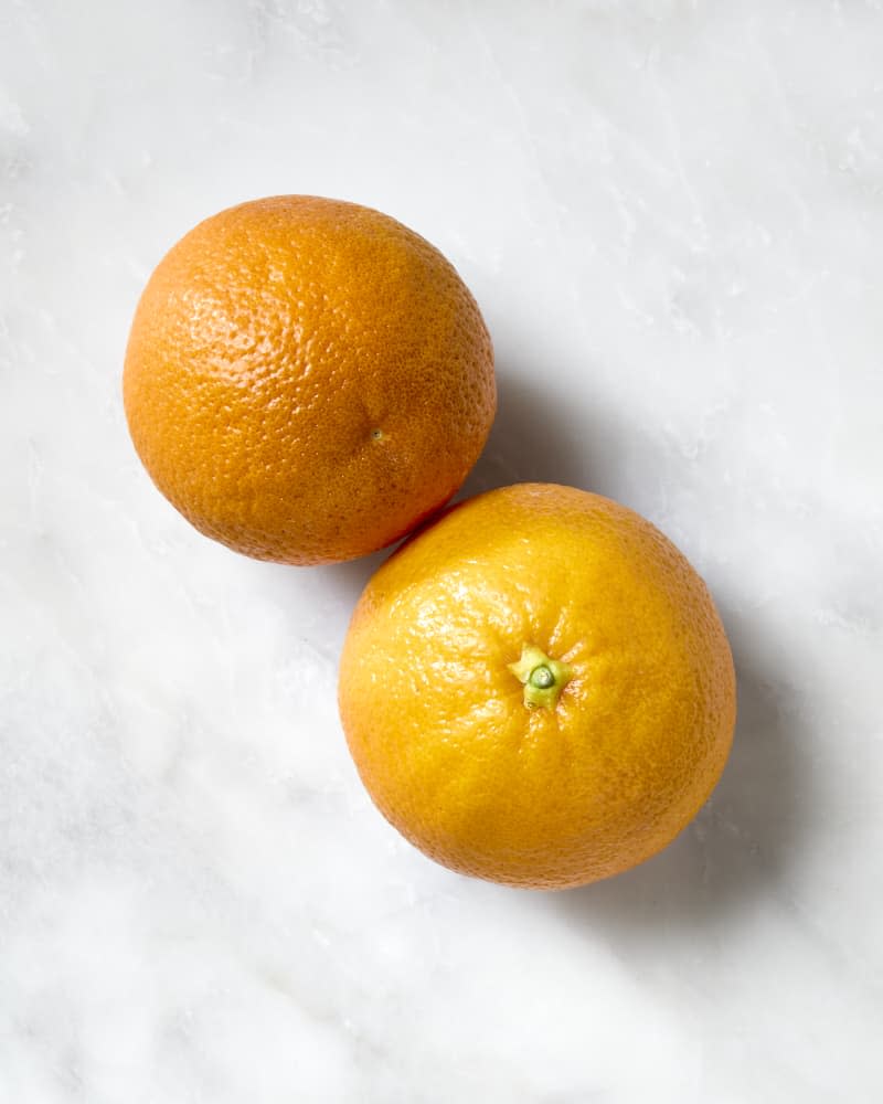 overhead shot of two blood oranges on a white marble surface.