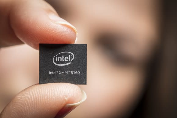 A person holding a chip between their fingers that reads: "Intel XMM 8160."
